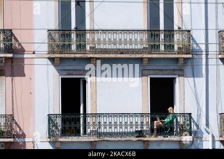 JUNGE FRAU, BALKON, URLAUB, LAPTOP: Eine Frau arbeitet an einem Laptop auf einem Balkon mit Blick auf die Promenade Tejo in Lissabon. Foto: Rob Watkins Stockfoto