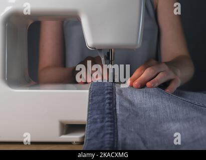 Arbeiten mit Denim-Textil an der Nähmaschine. Modisches Design. Stockfoto