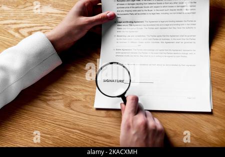 Vertragsunterzeichnung. Wortsignatur durch Lupe auf Geschäftsdokumenten. Stockfoto