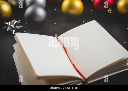 Neujahrskonzept und Hintergrund mit Weihnachtsschmuck und Notizbuch. Stockfoto