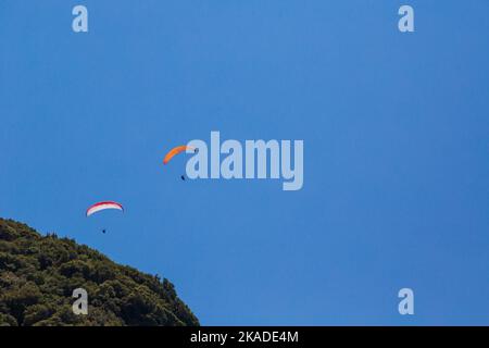 Tandem-Paragliding gegen einen blauen Himmel, sonnigen Tag. Zwei Gleitschirme am Himmel. Stockfoto