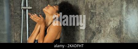 Lockige afroamerikanische Frau mit geschlossenen Augen Dusche zu Hause, Banner, Stockbild Stockfoto