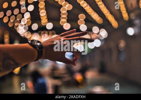 Eine Nahaufnahme einer Hand, die das OK-Zeichen im Hintergrund der Bokeh-Lichter zeigt. Stockfoto