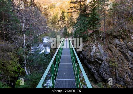 Gorges de l'Areuse, Noiraigue , Neuchatel, Schweiz, Europa. Metallbrücke über den Fluss mit herbstlicher Jura-Berglandschaft. Stockfoto