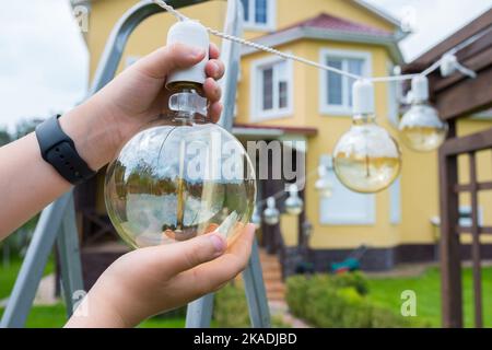 Glühlampe in der Hand Nahaufnahme. Hinterhof-Reinigung Stockfoto
