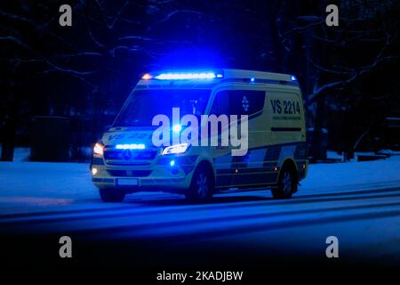 Mercedes-Benz Ambulanz auf der Straße in der Dunkelheit einer Winternacht mit blauen Lichtern blinkend. Salo, Finnland. 28. Dezember 2021. Stockfoto