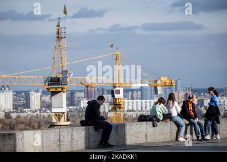 28. Oktober 2022, Kiew, Ukraine: Menschen sitzen auf einer Brüstung in einem Park im Zentrum von Kiew. Im Oktober 2022 führten die russischen Streitkräfte zahlreiche Angriffe auf die zivile Infrastruktur von Kiew durch, die massive Stromausfälle, Wasserversorgung und Heizung in der Stadt verursachten. (Bild: © Oleksii Chumachenko/SOPA Images via ZUMA Press Wire) Stockfoto