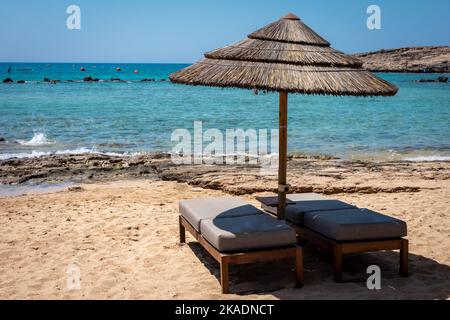 BlueOrange studio: Liegestühle und ein orangener Sonnenschirm an einem  schönen tropischen Strand auf den Malediven 