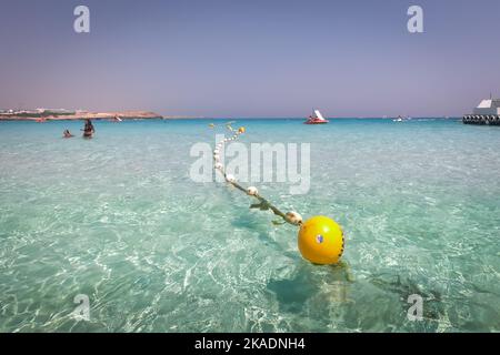 Im Meer schwimmende Markierungsbojen. Türkisfarbenes Wasser und goldener Sand am Nissi Beach, Zypern. Stockfoto