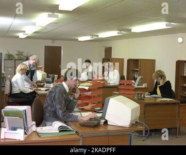 1990, historische Großraumbüros, männliche und weibliche Mitarbeiter, die an Schreibtischen arbeiten, einige am Telefon und mit Computerterminals der damaligen Zeit, England, Großbritannien. Stockfoto