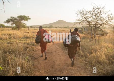 MASSAI MIT REISETASCHEN VON TOURISTEN Stockfoto