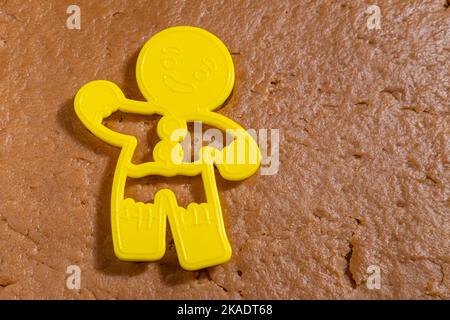 Yellow Gingerbread man Form zum Ausschneiden von rohem Lebkuchenteig. Kochen hausgemachter Lebkuchen zu Hause. Weihnachtsplätzchen Stockfoto