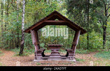 Kleines Holzpicknickhaus im Herbstwald vor dem Hintergrund der fallenden gelben Blätter im Wald Stockfoto
