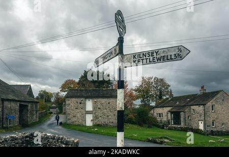 Ruhiges Dorfzentrum von Conistone mit attraktiven Steinobjekten aus dem 18.. Jahrhundert und einem traditionellen Wegweiser in verschiedene Richtungen - Wharfedale, Stockfoto