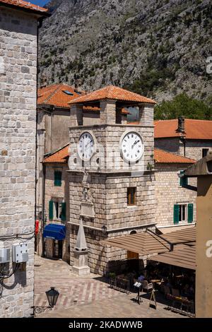 Kotor Montenegro - 29. April 2022: Uhrenturm auf dem Platz in der Altstadt von Kotor. Mittelalterliche Architektur, Steinmauern und orangefarbene Ziegeldächer. Stockfoto