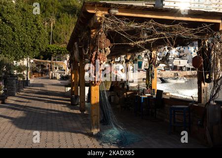 Budva, Montenegro - 28. April 2022: Fischer reparieren seine Netze an der Strandpromenade Rafailovici. Stockfoto