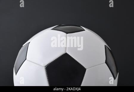 Detailansicht des halbklassischen Fußballs aus schwarzem und weißem Leder auf schwarzem Hintergrund isoliert. Vorderansicht. Stockfoto