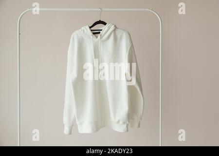 Weißer Hoodie, Sweatshirt Mock-Up, aufgehängt an weißem Rack Hanger, Vorderansicht Stockfoto