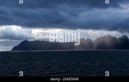 Eine wunderschöne Aufnahme einer Wolkenlandschaft über einem Meer mit ruhigen Wellen und Bergen in Norwegen Stockfoto