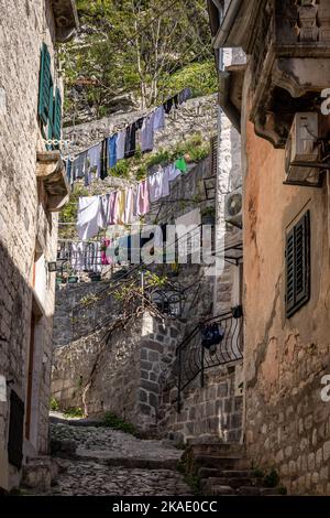 Kotor, Montenegro - 29. April 2022: Farbenfrohe Wäscherei hängt von mittelalterlichen Steinhäusern in einer engen Altstadt. Stockfoto