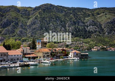 Kotor, Montenegro - 29. April 2022: Segelyachten, Motorboote und kleine Fischerboote liegen am Pier in der Bucht von Kotor vor. Berge im Hintergrund. Stockfoto