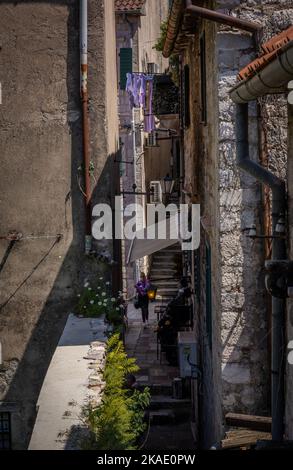 Kotor, Montenegro - 29. April 2022: Eine Frau, die eine sehr enge Straße in der Altstadt von Kotor entlang geht. Stockfoto