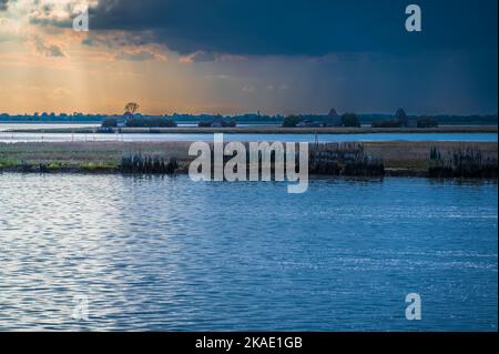 Gegen den Sonnenuntergang. Marano Lagune Spätsommer Farben. Wolken und Sonne Stockfoto