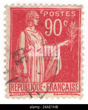 FRANKREICH - 1932: Eine dunkelrote Briefmarke mit 90 Rappen, die „Frieden mit Olivenzweig“ darstellt. La Paix, Allegorie der Republik, phrygische Mütze und einen Olivenzweig (Symbol des Friedens) haltend, in ihrer linken Hand, rechte Hand auf dem Griff ihres Schwertes in seiner Scheide, entworfen von Paul Albert Laurens, französischer Maler Stockfoto