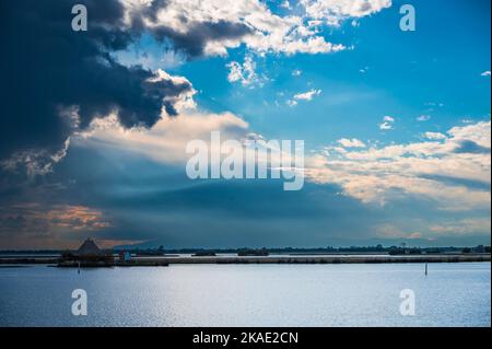 Gegen den Sonnenuntergang. Marano Lagune Spätsommer Farben. Wolken und Sonne Stockfoto