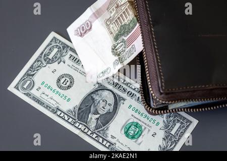 1 amerikanische Dollar-Banknote und 100 russische Rubel-Scheine in einem Geldbeutel auf dem Tisch. Stockfoto