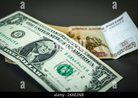 1 amerikanische Dollar-Banknote und 100 russische Rubel-Scheine auf dem Tisch. Stockfoto