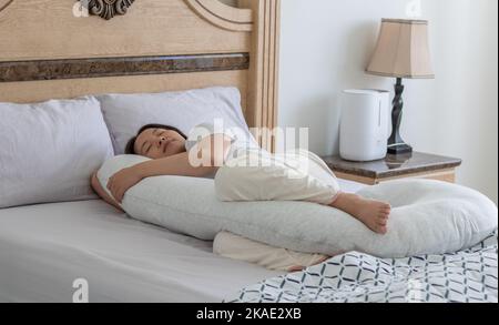 Nahaufnahme einer Schwangeren, die mit dem Schwangerschaftskissen auf dem Bett schläft Stockfoto