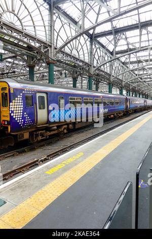 ScotRail-Zug am Bahnhofsplatz. „Mind the Gap“, geschrieben auf Platform, Glasgow, Schottland. Stockfoto