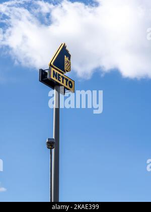 Breslau, Polen - 19. Februar 2022: Eine Spalte mit dem Logo eines Netto-Lebensmittelgeschäfts. Blauer Himmel mit Kopierraum. Stockfoto