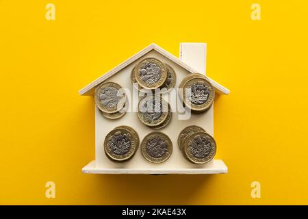 Lebenshaltungskosten. Vereinigtes Königreich Pfund Münzen auf einem Holzhaus Stockfoto