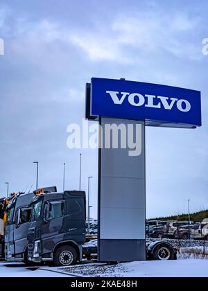 Reykjavik, Island - 25. Januar 2022: Eine Säule mit einem Logo der Volvo Car Corporation. Reihe geparkter Lastwagen im Hintergrund, Wintertag, keine Menschen. Stockfoto