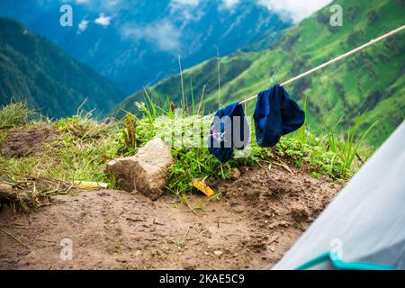 Juli 14. 2022, Himachal Pradesh Indien. Paar Trekkingsocken trocknen auf einem Draht nach einem langen Tag mit Landschaften und Himmel im Hintergrund. Stockfoto