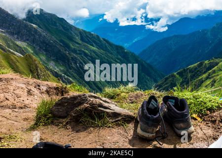 Juli 14. 2022, Himachal Pradesh Indien. Paar Trekkingschuhe und Socken auf einem Felsen mit Landschaften und Himmel im Hintergrund. Stockfoto