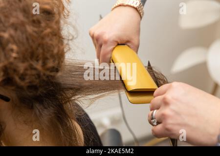 Haarglättung im Schönheitssalon. Keratin Recovery Haar-und Protein-Behandlung Stapel mit professionellen Ultraschall-Eisen-Tool. Stockfoto