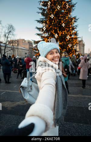 Folgen Sie mir Konzept Frau zieht Mann zum weihnachtsbaum Stockfoto