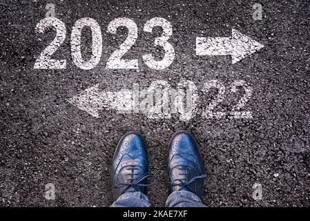 Richtung 2023 geschrieben auf Asphaltstraße Hintergrund mit Beinen, Neujahr Geschäftskonzept Stockfoto