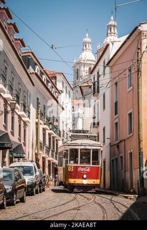 Eine vertikale Aufnahme einer Straßenbahn mit CocaCola-Werbung auf der Straßenbahn in den sonnigen gepflasterten Straßen von Lissabon, Portugal Stockfoto