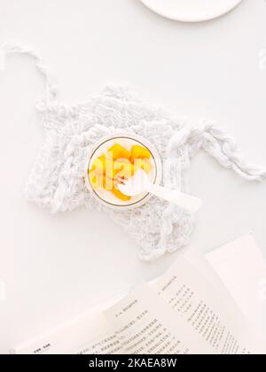 Eine vertikale Draufsicht auf köstliche Mangoscheiben mit einem Milchshake in einem Glas auf weißem Hintergrund Stockfoto
