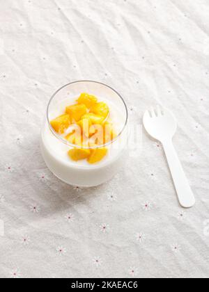 Eine vertikale Nahaufnahme von köstlichen Mangoscheiben mit einem Milchshake in einem Glas auf weißem Hintergrund Stockfoto