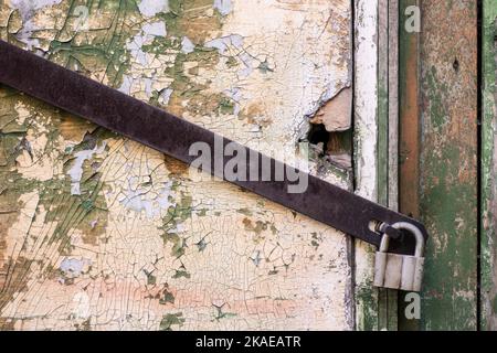 Altes verrosttes Vorhängeschloss und Metallfragmente an alten bunten Holztüren Stockfoto