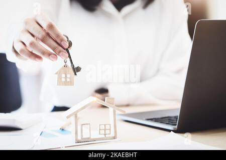 Immobilienmakler stimmen zu, ein Haus zu kaufen und den Kunden in den Büros ihrer Agentur Schlüssel zu geben. Konzeptvereinbarung. Stockfoto