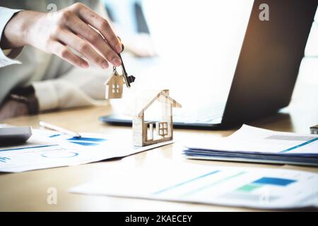 Immobilienmakler stimmen zu, ein Haus zu kaufen und den Kunden in den Büros ihrer Agentur Schlüssel zu geben. Konzeptvereinbarung. Stockfoto