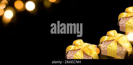 Werbebanner mit Geschenkkartons Reihe auf schwarzem Hintergrund mit goldenen Bokeh-Lichtern. Kreative Promotion-Mock-up von Urlaub Shopping und Verkauf. Leerzeichen f Stockfoto