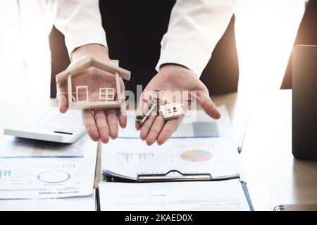 Immobilienmakler stimmen zu, ein Haus zu kaufen und den Kunden in den Büros ihrer Agentur Schlüssel zu geben. Konzeptvereinbarung. Stockfoto