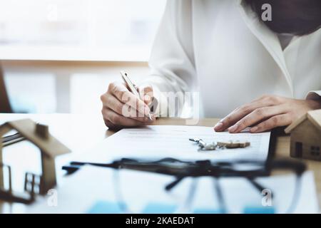 Der Kunde hält einen Stift in der Hand und liest den Kaufvertrag vor der Unterzeichnung. Stockfoto